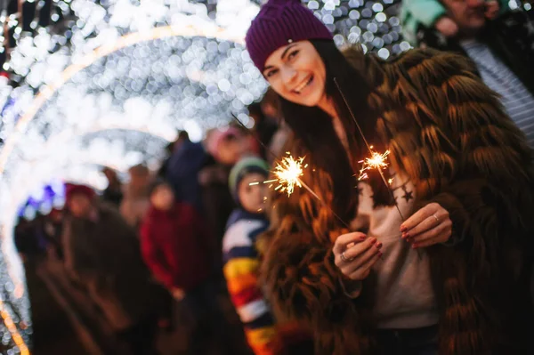 Noel panayırının yanında elinde pırıltılarla duran güzel genç bayan. 