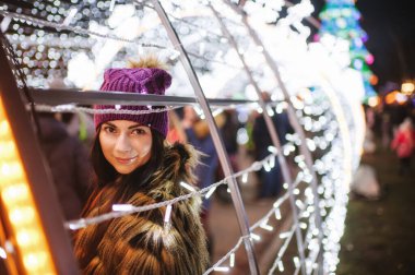 Güzel genç bayan Noel panayırının yanında duruyor. 