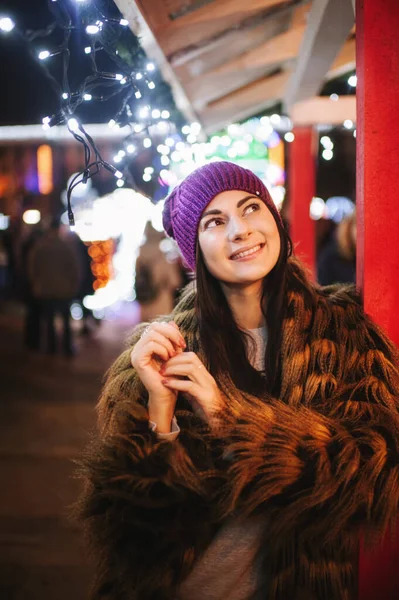 Güzel genç bayan Noel panayırının yanında duruyor. 