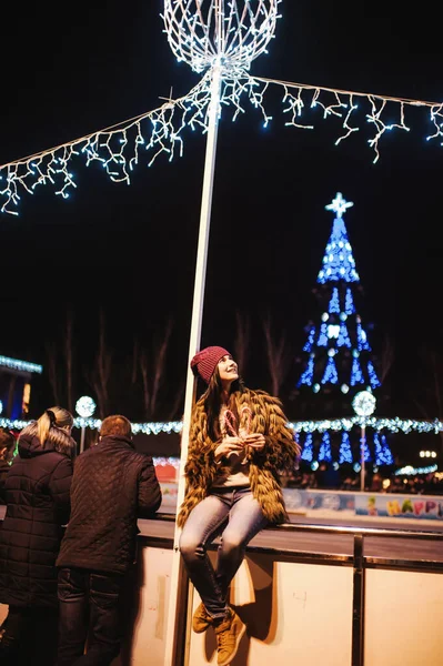 Güzel genç bayan Noel panayırının yanında duruyor. 