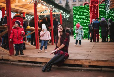 Güzel genç bayan Noel evinin yanında duruyor ve iki tane Noel şekeri saklıyor. 