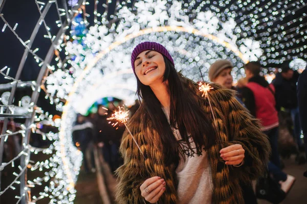 Noel panayırının yanında elinde pırıltılarla duran güzel genç bayan. 
