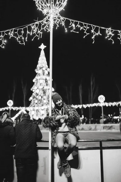 Güzel genç bayan Noel panayırının yanında duruyor. 