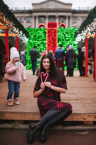 Güzel genç bayan Noel evinin yanında duruyor ve iki tane Noel şekeri saklıyor. 