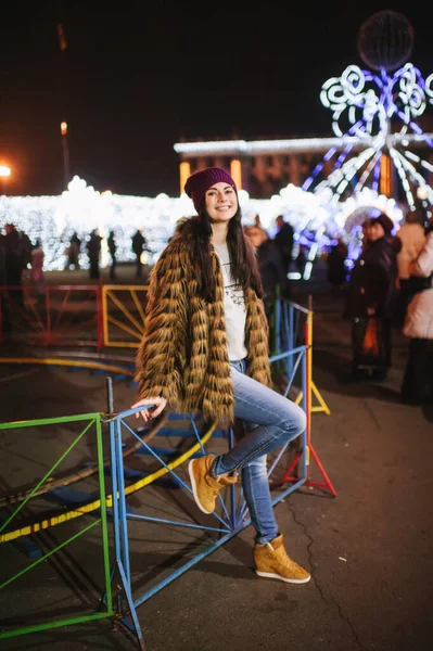 Güzel genç bayan Noel panayırının yanında duruyor. 