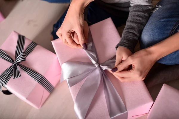 Anne ve kızının elleri bir hediye paketliyor.