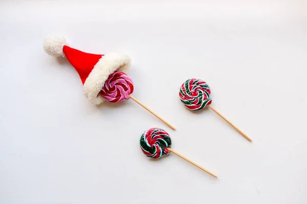 Beyaz arka plandaki şekerler. Bir şekerin üstünde küçük bir Noel Baba şapkası var.