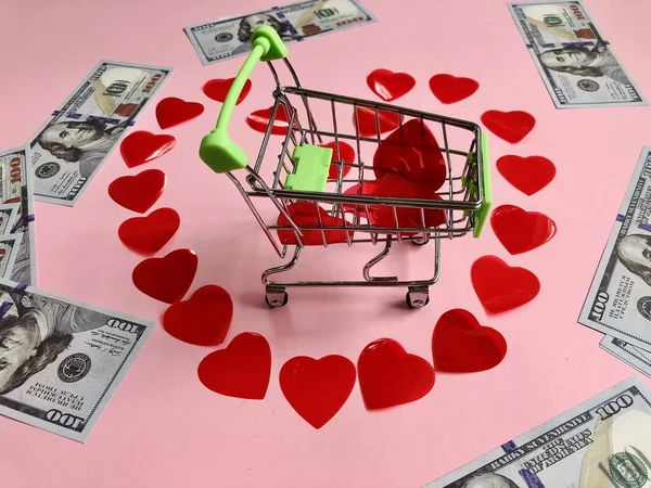 Carrello della spesa al centro del cuore fatto di piccoli cuori rossi e banconote da cento dollari — Foto Stock