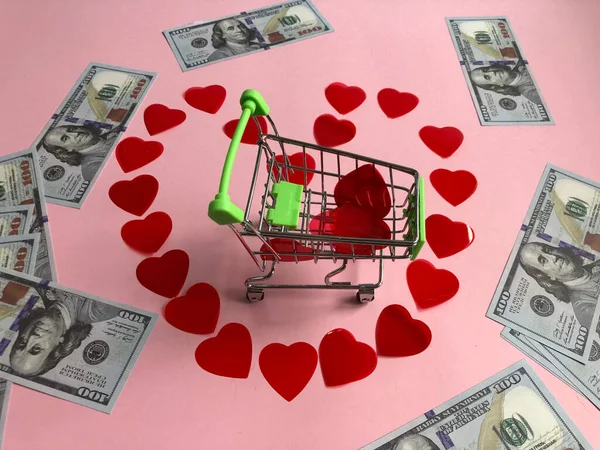 Carrello della spesa al centro del cuore fatto di piccoli cuori rossi e banconote da cento dollari — Foto Stock