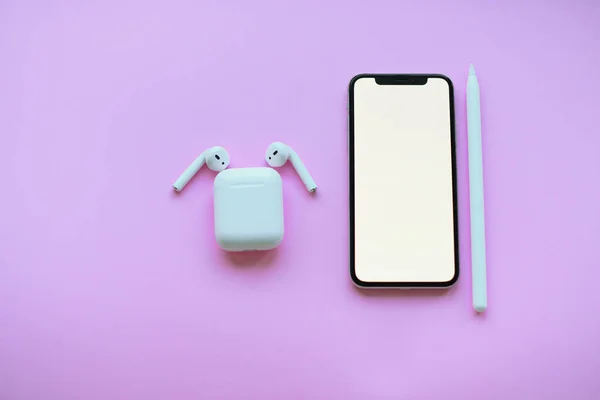 Modelleme. iPhone, hava kapsülleri ve pembe arka planda elma kalemi.