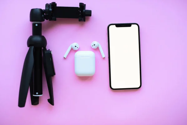 Mochup. Tripod, hava kapsülleri ve pembe arka planda telefon. Yüksek kalite fotoğraf