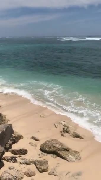 Una playa rocosa al lado del océano.Dos chicos van a surfear al océano. — Vídeos de Stock