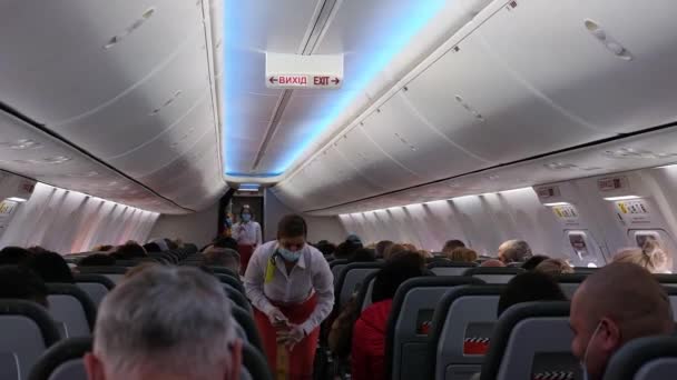 V letadle letuška v lékařské masce ukazuje bezpečnostní techniku letadla — Stock video