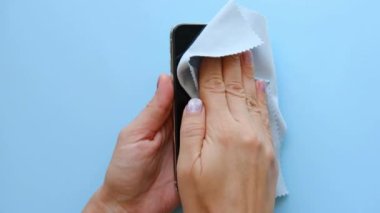 Kadınlar mavi arka planda özel bir temizlik beziyle akıllı telefon X 'ini temizliyor. 23 Mayıs 2021' in en iyi görüntüsü..