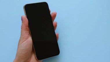 Kadınlar mavi arka planda özel bir temizlik beziyle akıllı telefon X 'ini temizliyor. 23 Mayıs 2021' in en iyi görüntüsü..