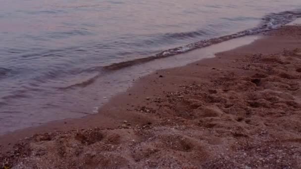 Textura de la superficie del agua, ondulaciones y olas, textura de arena del lado del mar rojo, puesta del sol brillan fondo de agua. Playa roja y arena — Vídeos de Stock