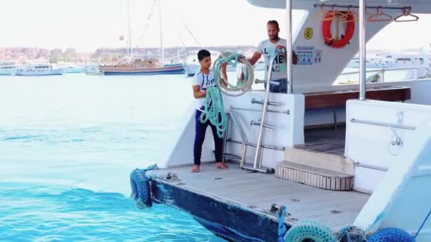 Молоді чоловіки, які швартують яхту на берег мотузкою в Єгипті Sharm El Sheikh 16 квітня 2021. — стокове відео