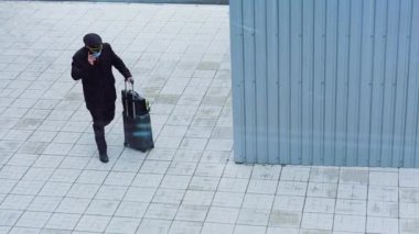 Üniformalı ve tıbbi maskeli pilot bavuluyla Ukrayna havaalanına gider ve telefonuyla konuşur. 
