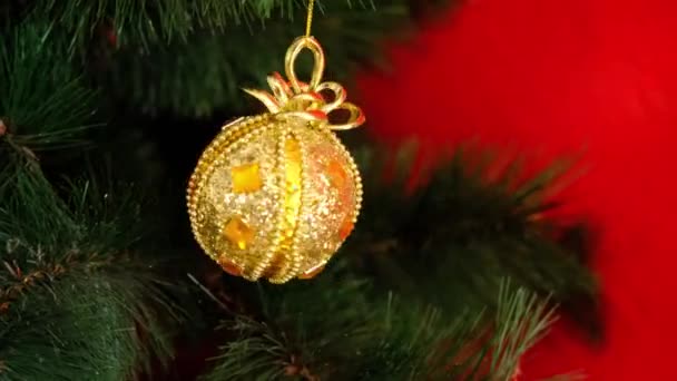 Złoty oświetlenie żółty Christmas zabawka przędzenia na zielonej gałęzi na czerwonym tle — Wideo stockowe