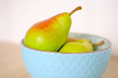 Ahşap zemindeki mavi seramik tabakta olgun armutlar 