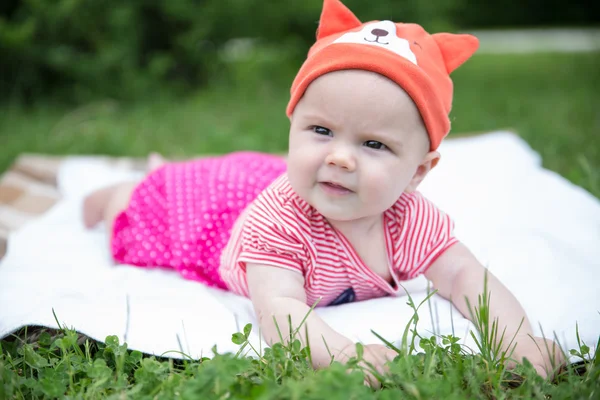 Babymädchen krabbelt mit lustigem Hut auf dem Gras — Stockfoto