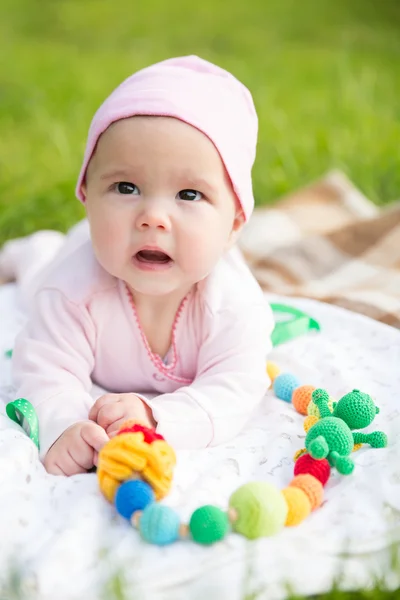 Bébé fille rampant sur l'herbe avec des perles fronde — Photo