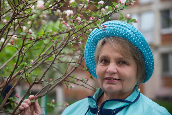 Aktif yaşlı kadın mavi şapka giyiyor — Stok fotoğraf