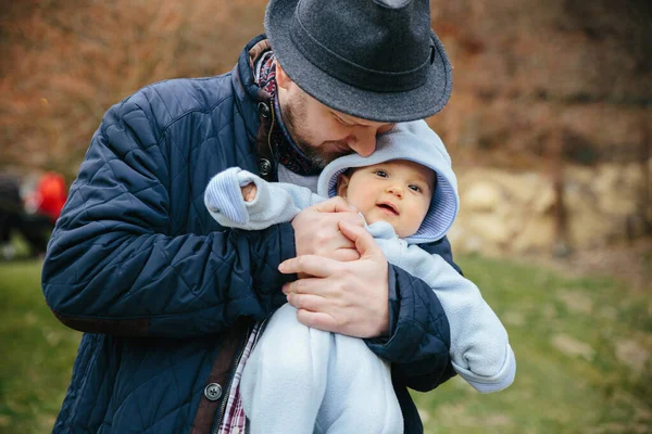 Father hugs little son outside. Wearing hat and jacket — Stock Photo, Image