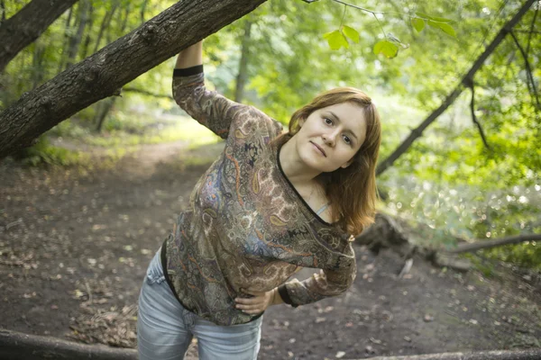 Attraktiv ung kvinna njuter sommarkväll under ett träd med gröna blad och tittar i kameran — Stockfoto