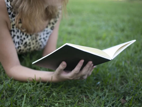 Meisje het lezen van boek en liggen op gras in de zomer park — Stockfoto