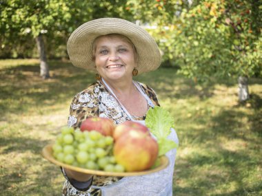elma ve üzüm plaka üzerinde gösterilen ülkenin gülümseyen yaşlı kadın. meyve bulanık