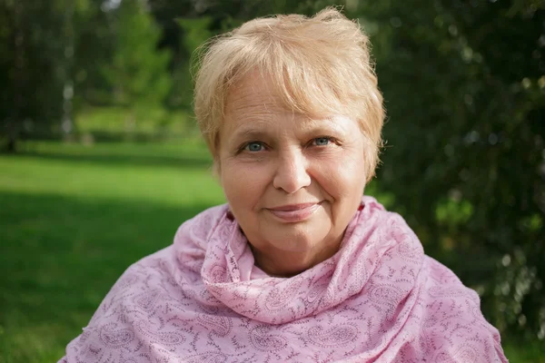 Porträtt av glad ganska senior kvinna i parken på natur bakgrund — Stockfoto