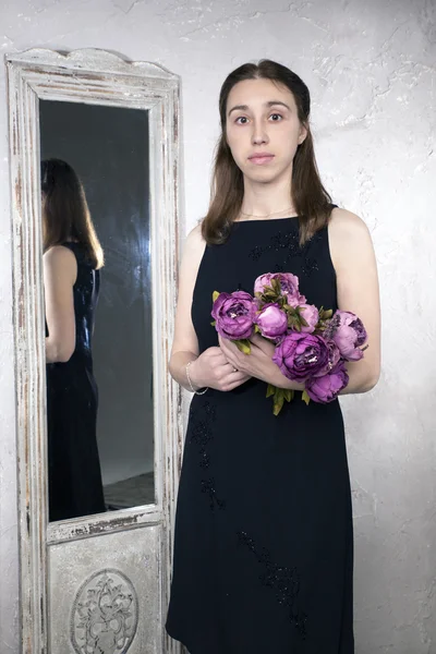 Portrait of a young Caucasian woman with the mirror and flower