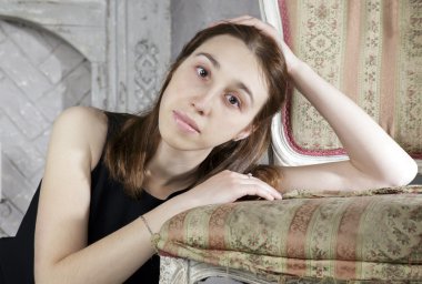 Şömine yakın vintage sandalye ile genç beyaz bir kadın portresi