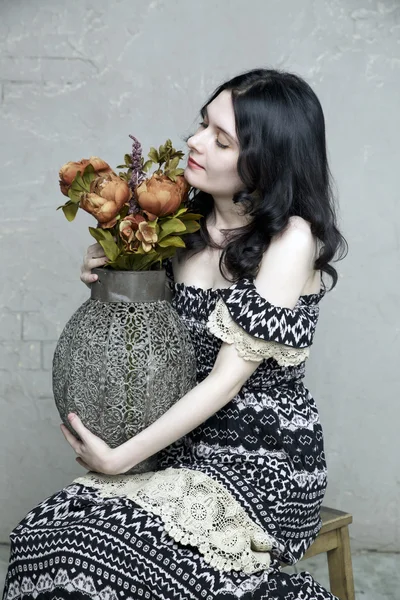 Mujer morena sosteniendo florero vintage de flores — Foto de Stock