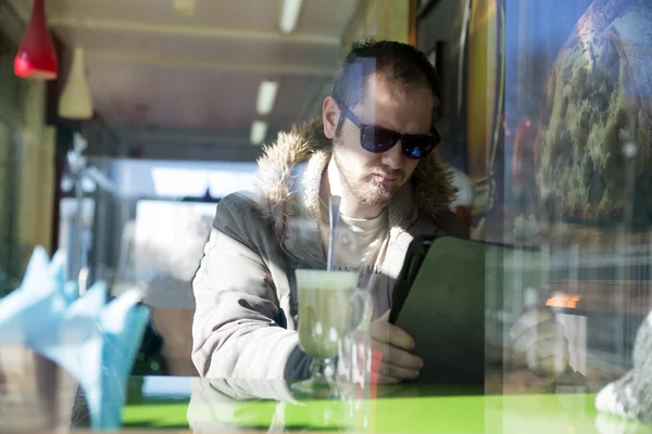 Російський мужик з бородою сидять усередині кафе в окулярах — стокове фото