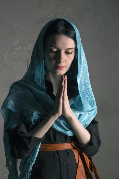 Beautiful young woman in a blue  shawl praying — Stock Photo, Image