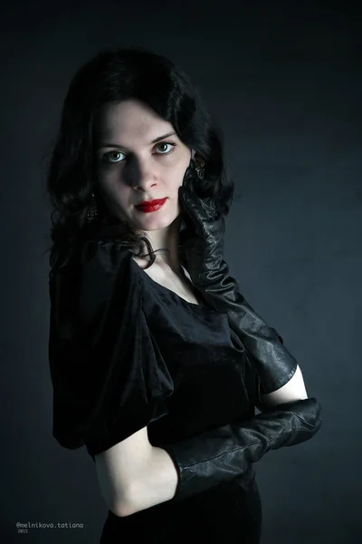 Schönes Mädchen in modischem Stil in schwarzem Kleid und Handschuhen — Stockfoto