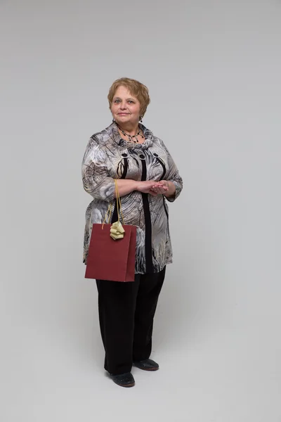 Portrait of an elderly happy woman on a grey background — Stockfoto