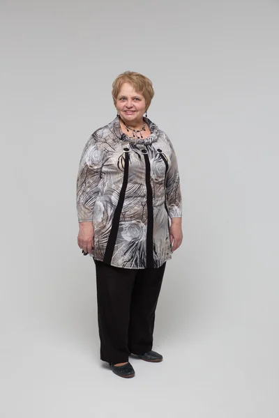Portrait of an elderly happy woman on a grey background Royaltyfria Stockfoton