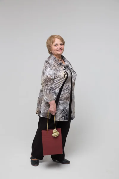 Portrait of an elderly happy woman on a grey background Stockbild