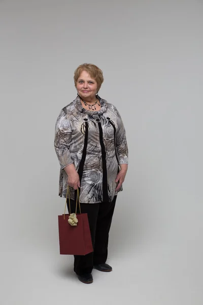 Portrait of an elderly happy woman on a grey background — Stockfoto