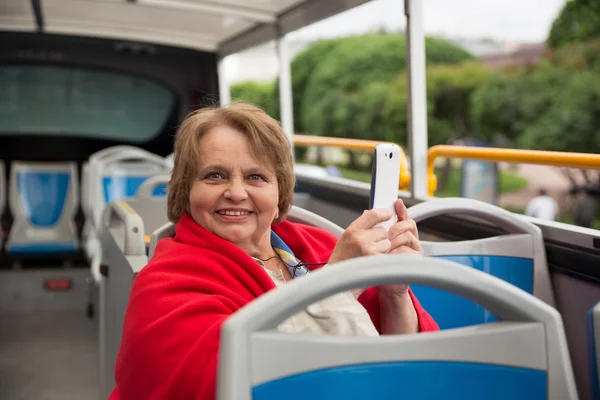 Äldre kvinna med telefonen på en turnébuss, Sankt-Petersburg, Ryssland Royaltyfria Stockfoton