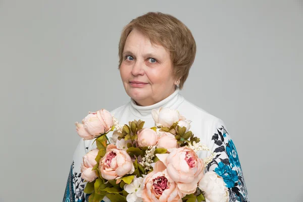 笑みを浮かべて、花の花束を手に保持している老婦人 — ストック写真