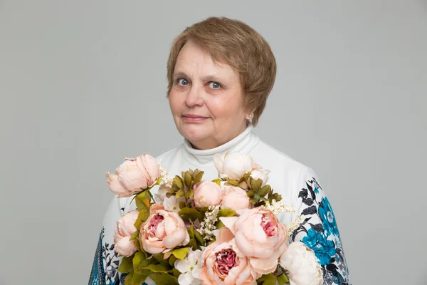 Gamla damen ler, hålla blombukett i handen — Stockfoto