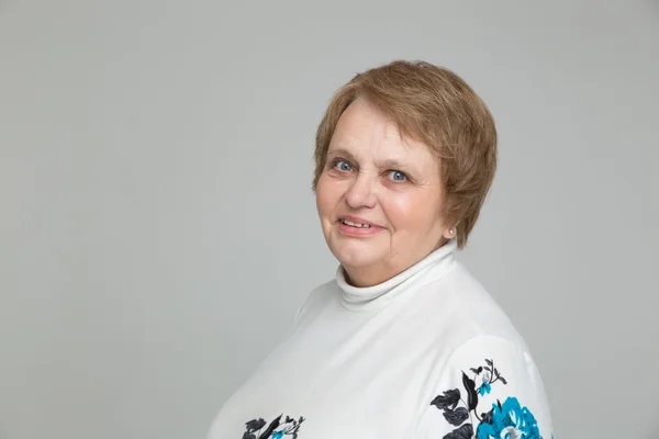 Retrato de una mujer rusa mayor en vestido blanco sobre fondo gris — Foto de Stock