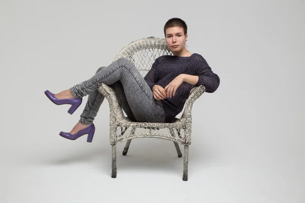 Flickan sitter i stol, isolerad på grå bakgrund — Stockfoto