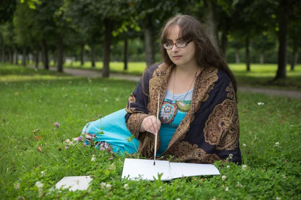 Jovem com livro no parque ensolarado verde — Fotografia de Stock