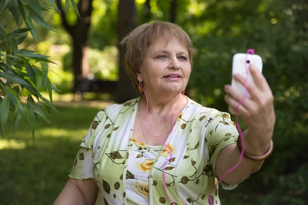 Щасливий старший пенсіонер розважається з мобільними та навушниками — стокове фото