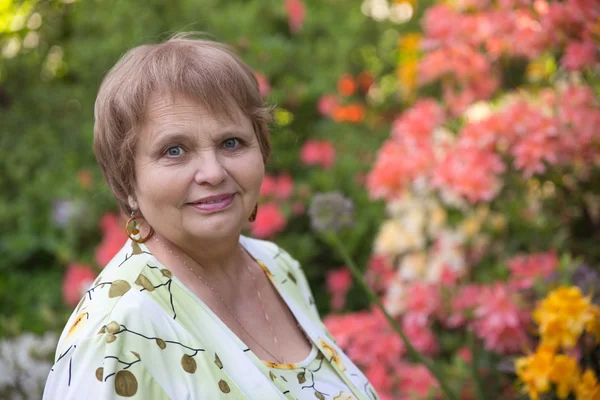 Emekli kadın çiçek bahçesinde — Stok fotoğraf